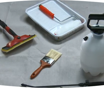 Paint roller sitting in a paint tray and a paint brush sitting on the ground