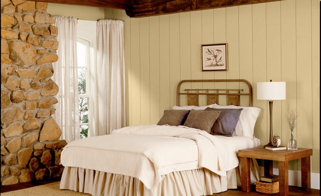 Bedroom with vertically paneled and stone walls