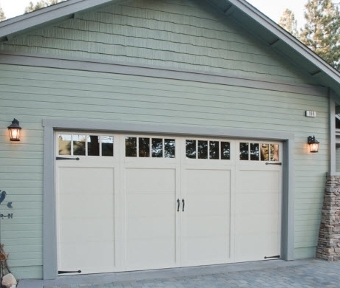 Image of exterior of a garage and garage door with teal siding.