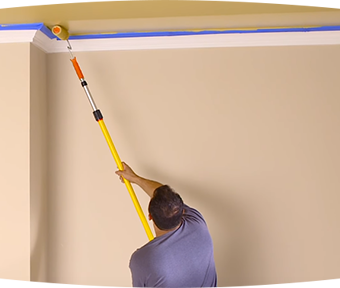 A man painting a ceiling with extension roller