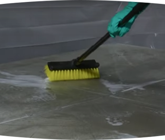 Person scrubbing the floor with a large brush
