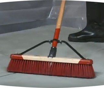Person using a large broom to sweep the floor