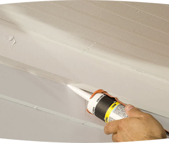 Person applying a gel to the exterior of a house between the siding and the floor