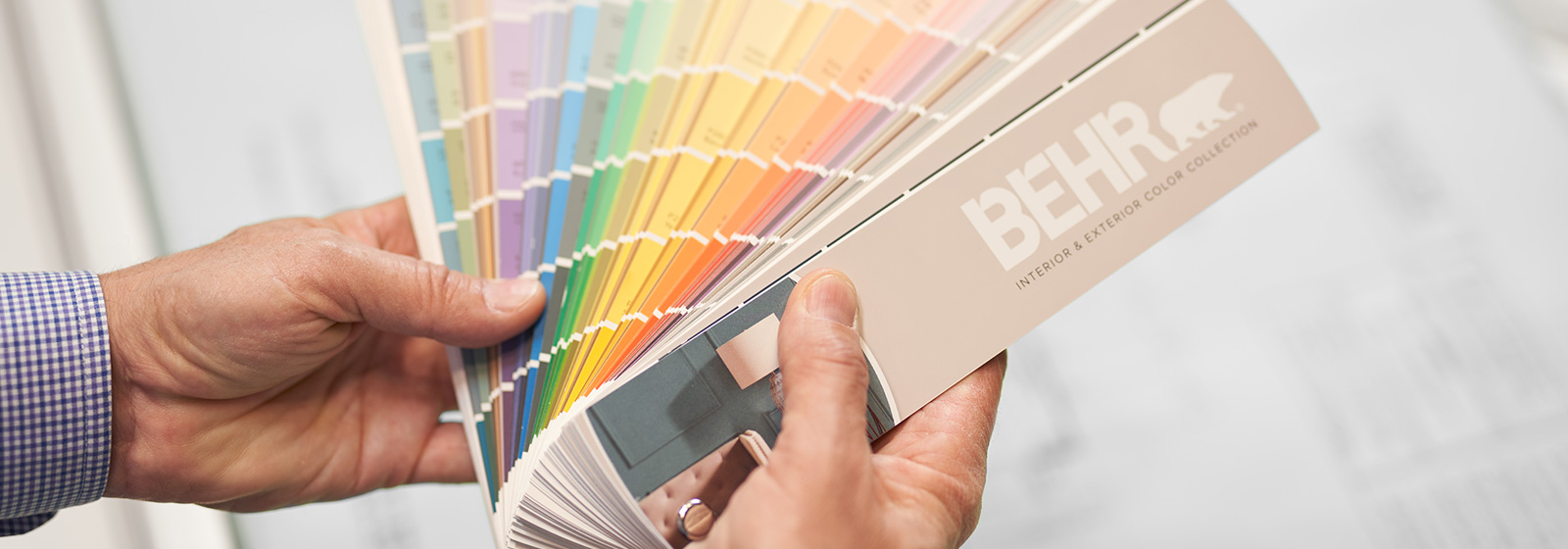 A large image of a BEHR Color Fan Deck held by a hand.