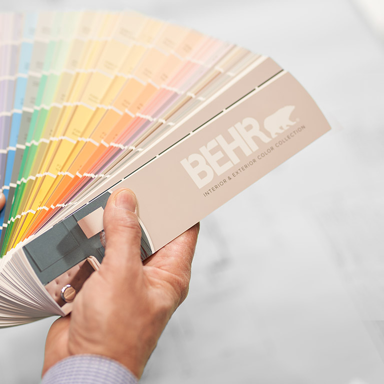 A small image of a BEHR Color Fan Deck held by a hand.
