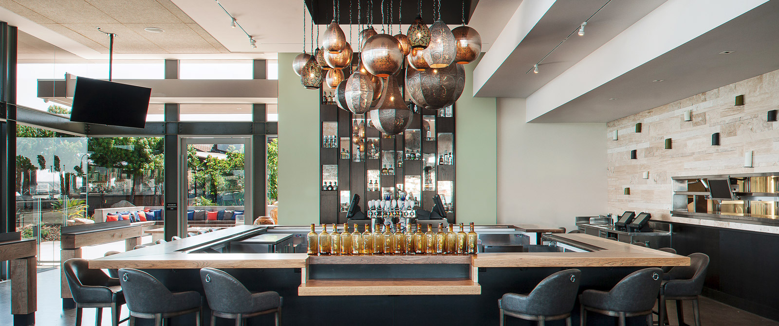 Image of an empty modern bar. In the middle of a bar there are Moroccan lamps hanging from the ceiling and you can see the outside from the inside of the bar