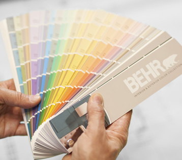 A BEHR Color Fan Deck held by a hand.