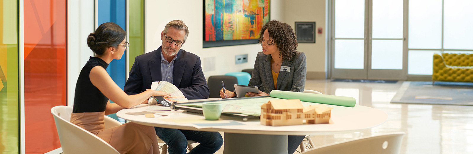 Large image of 3 seated architects in an meeting room discussuing colors and looking at a BEHR Fan Deck