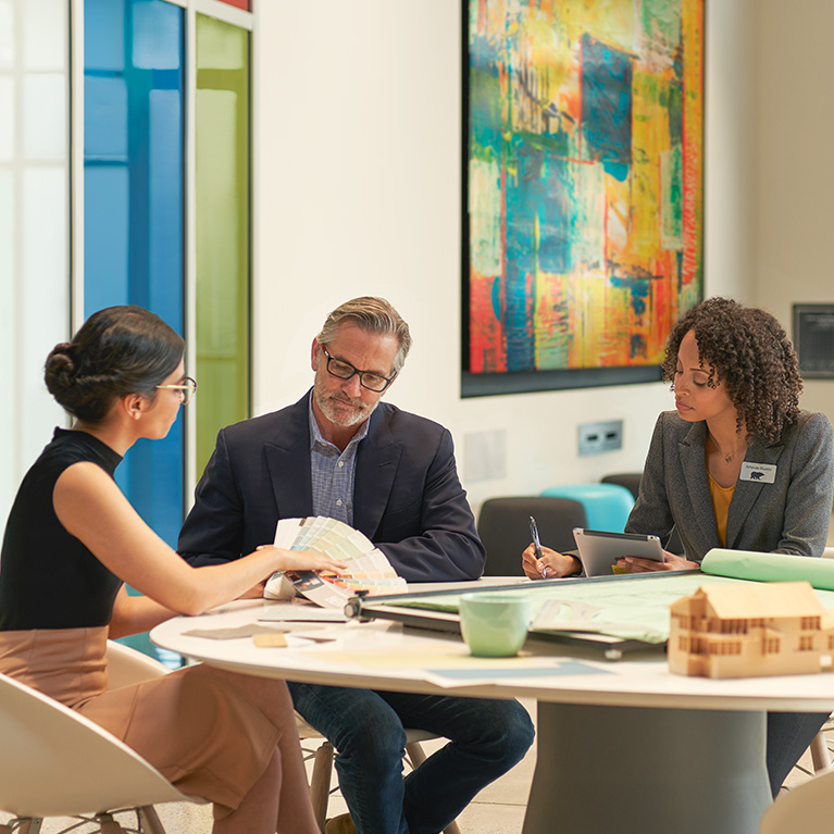 Small image of 3 seated architects in an meeting room discussuing colors and looking at a BEHR Fan Deck