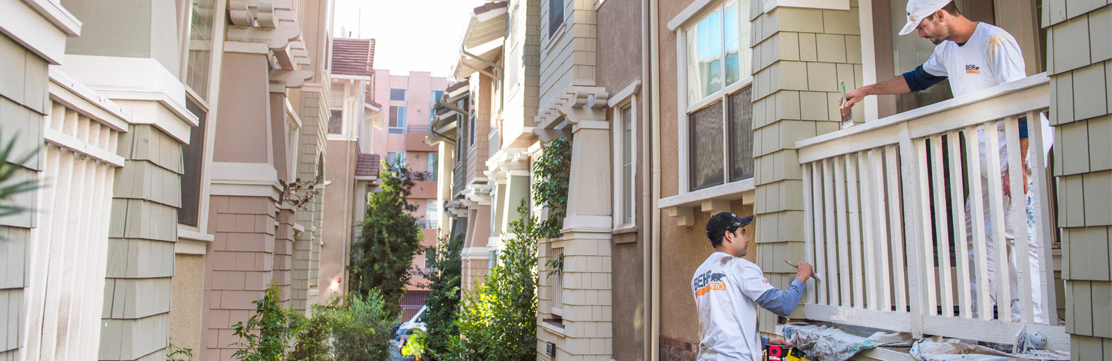 Large image of 2 Pro painters painting the wooden railings of the exterior of an apartment block.