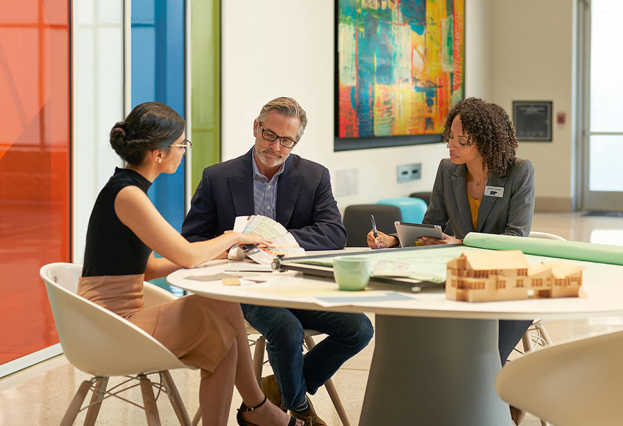 A small image of 3 seated architects in an meeting room discussuing colors and looking at a BEHR Fan Deck
