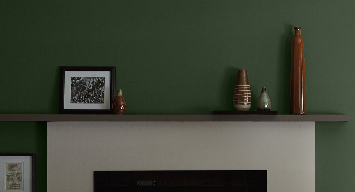 A white cement fireplace against a green painted wall. The mood is quiet and peaceful.